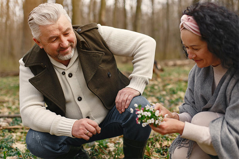 man and woman squatted down near the ground to pick wildflowers